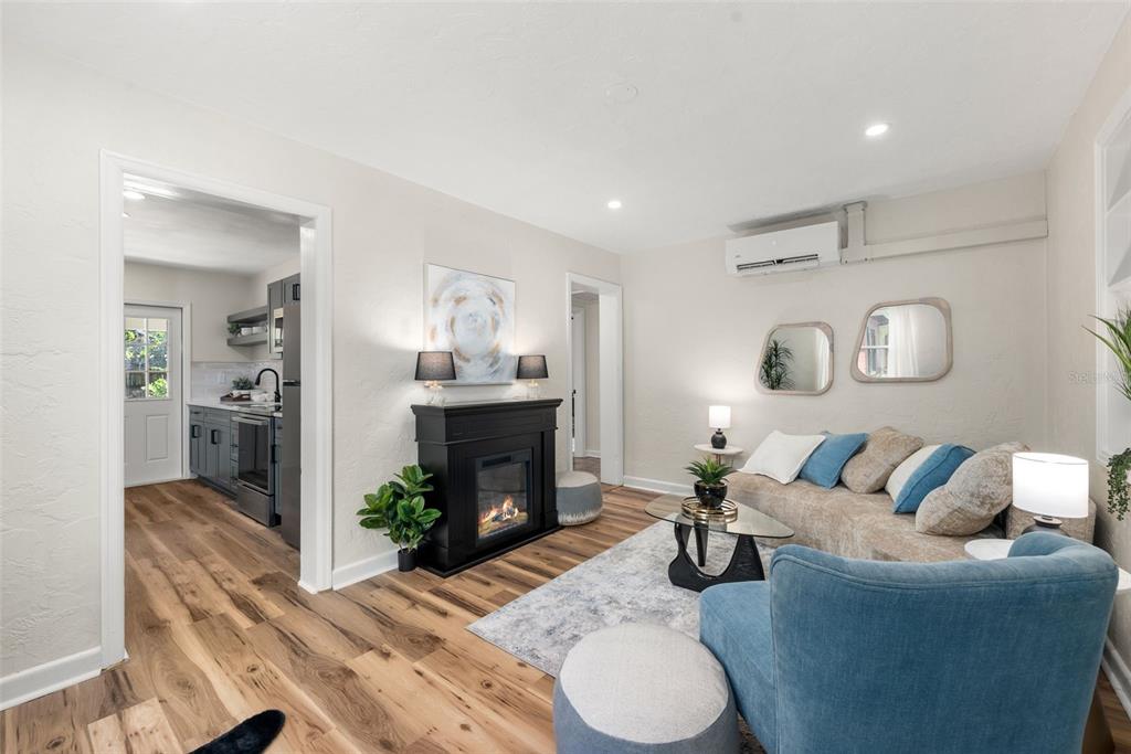 A living room with wood floors, a black fireplace, and a blue armchair and sofa — 807 NW 24TH AVENUE, GAINESVILLE, FL