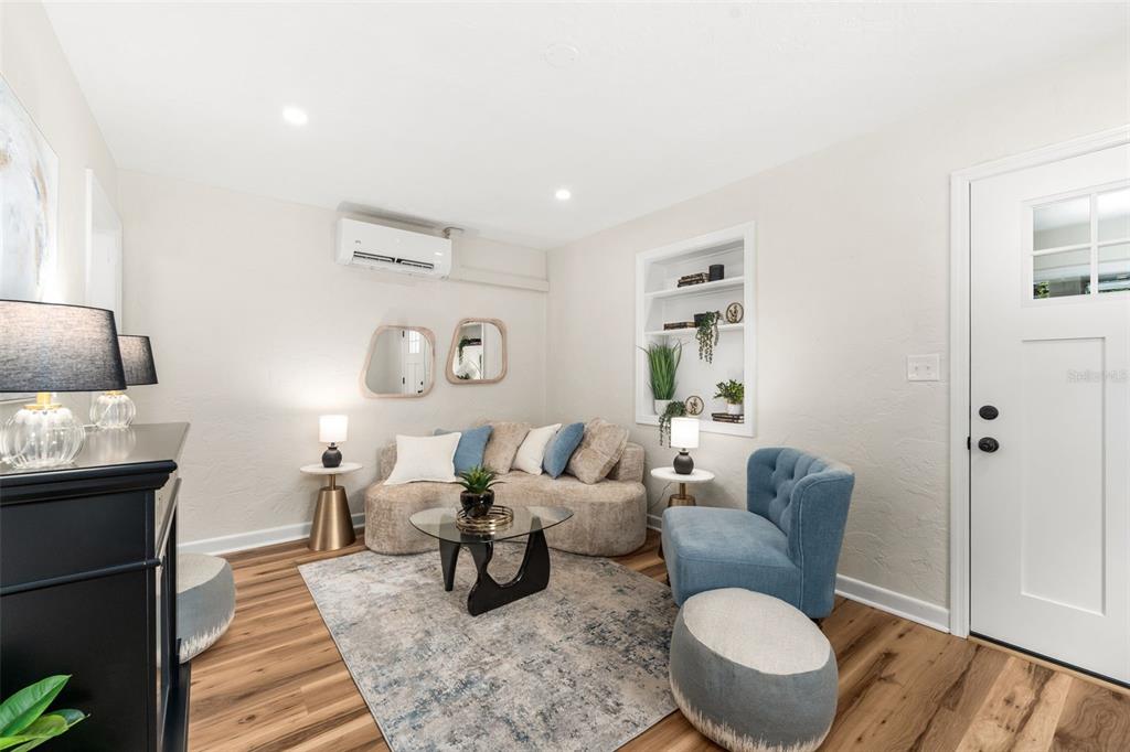 A living room features a curved sofa, blue accent chair, wall niche, and wood flooring — 807 NW 24TH AVENUE, GAINESVILLE, FL
