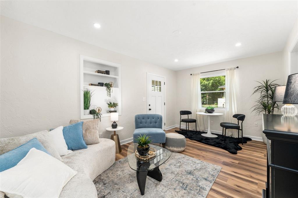 A living room features a curved sofa, a glass coffee table, and a small dining area — 807 NW 24TH AVENUE, GAINESVILLE, FL