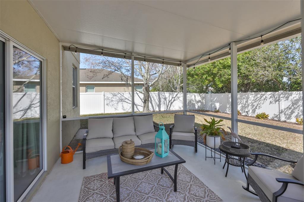 A screened-in patio features a sofa, chairs, a coffee table, and a view of the backyard — 1609 BONITA BLUFF COURT, RUSKIN, FL