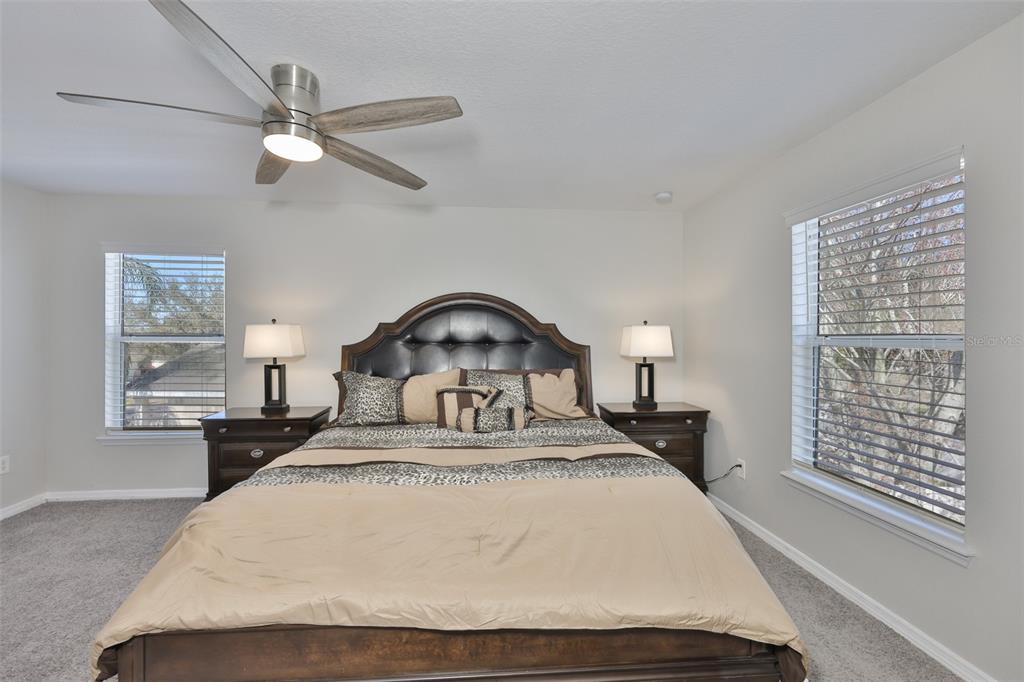 A bedroom features a dark wood bed frame, two nightstands with lamps, and a ceiling fan — 1609 BONITA BLUFF COURT, RUSKIN, FL