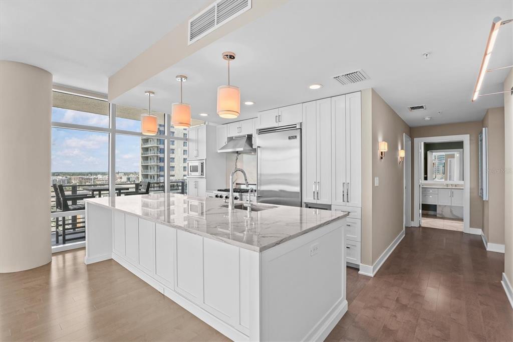 A modern kitchen features a large marble-topped island, white cabinetry, and floor-to-ceiling windows — 1120 E KENNEDY BOULEVARD UNIT 1216, TAMPA, FL