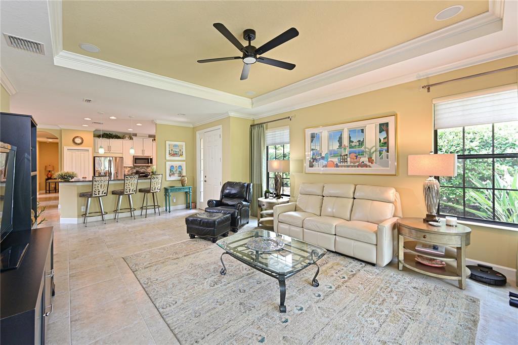 A living room with a beige sofa, glass coffee table, and an open kitchen area — 5007 SERATA DRIVE, BRADENTON, FL