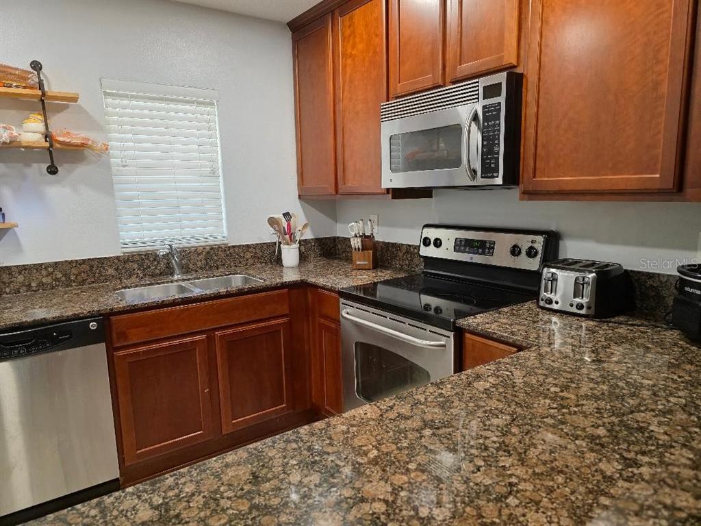A kitchen features wood cabinets, granite countertops, stainless steel appliances, and a double sink — 37613 AARALYN ROAD, ZEPHYRHILLS, FL