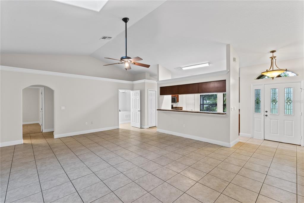 A spacious living area features tile flooring, a vaulted ceiling, and an open kitchen pass-through — 4924 RAYLENE WAY, ST CLOUD, FL