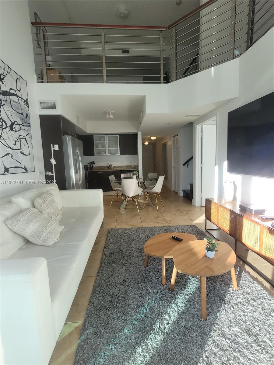 A living room with a white sofa, a grey rug, and a lofted mezzanine level — 41 SE 5th St # 710, Miami FL 33131, MIAMI, FL
