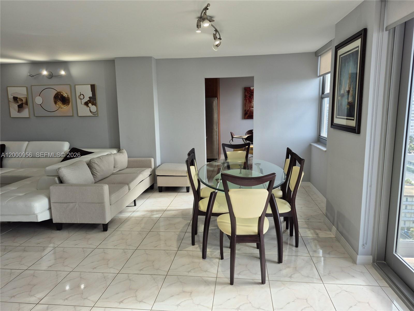 A living and dining area features light gray walls, tile flooring, and modern furniture — 1912 S Ocean Dr # 17C, Hallandale Beach FL 33009, HALLANDALE BEACH, FL