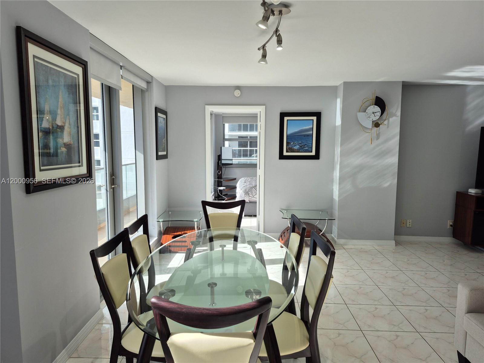 A dining room features a glass-topped table, six chairs, tiled floors, and a balcony view — 1912 S Ocean Dr # 17C, Hallandale Beach FL 33009, HALLANDALE BEACH, FL