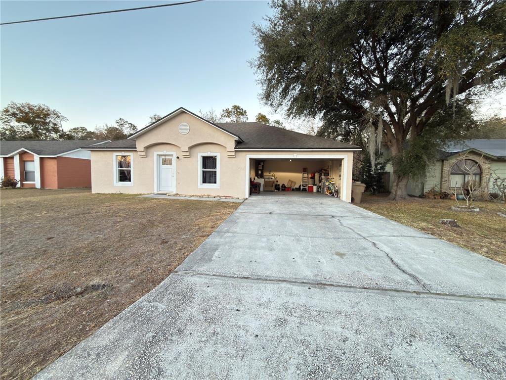 A single-story house with a beige stucco exterior, a front-facing garage, and a concrete driveway — 796 DEL PRADO DRIVE, KISSIMMEE, FL