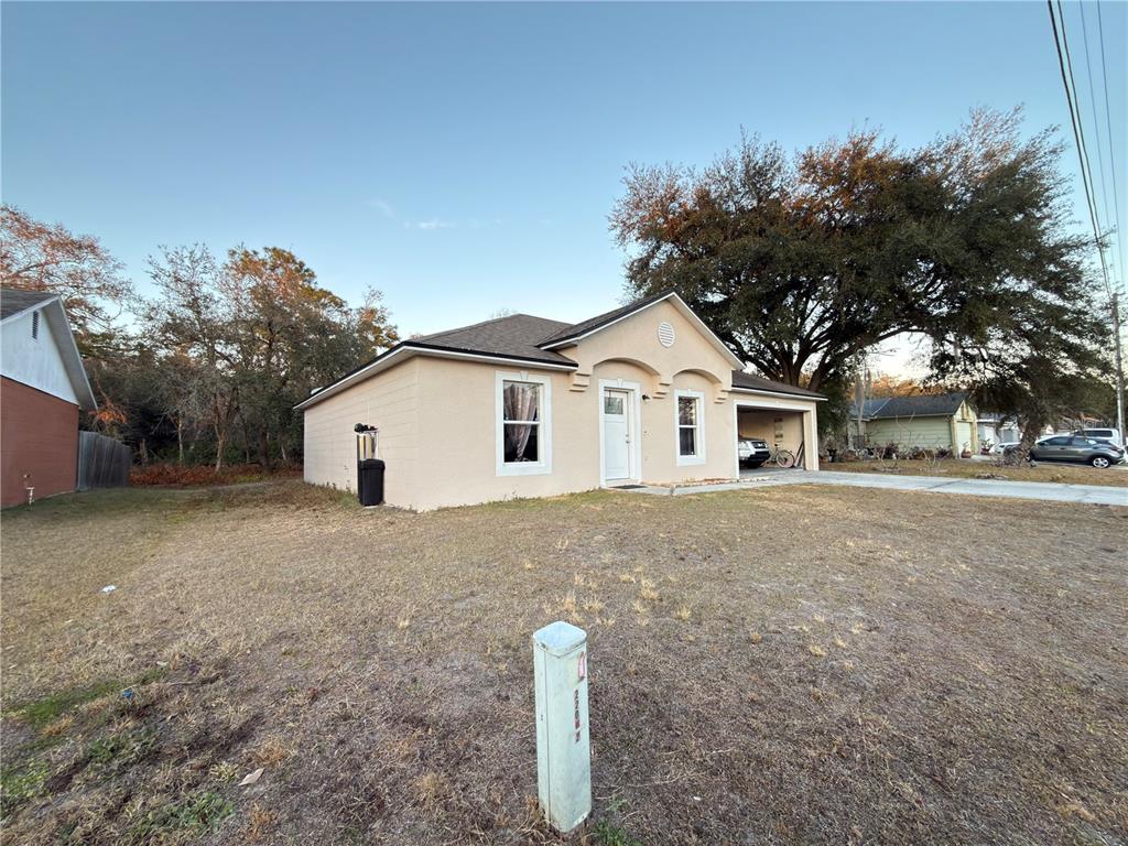 A single-story beige house with a front-facing garage and a large tree in the yard — 796 DEL PRADO DRIVE, KISSIMMEE, FL