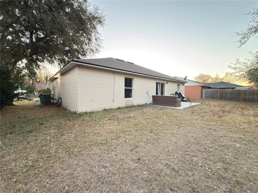 The exterior of a beige concrete block house features a small patio and backyard — 796 DEL PRADO DRIVE, KISSIMMEE, FL