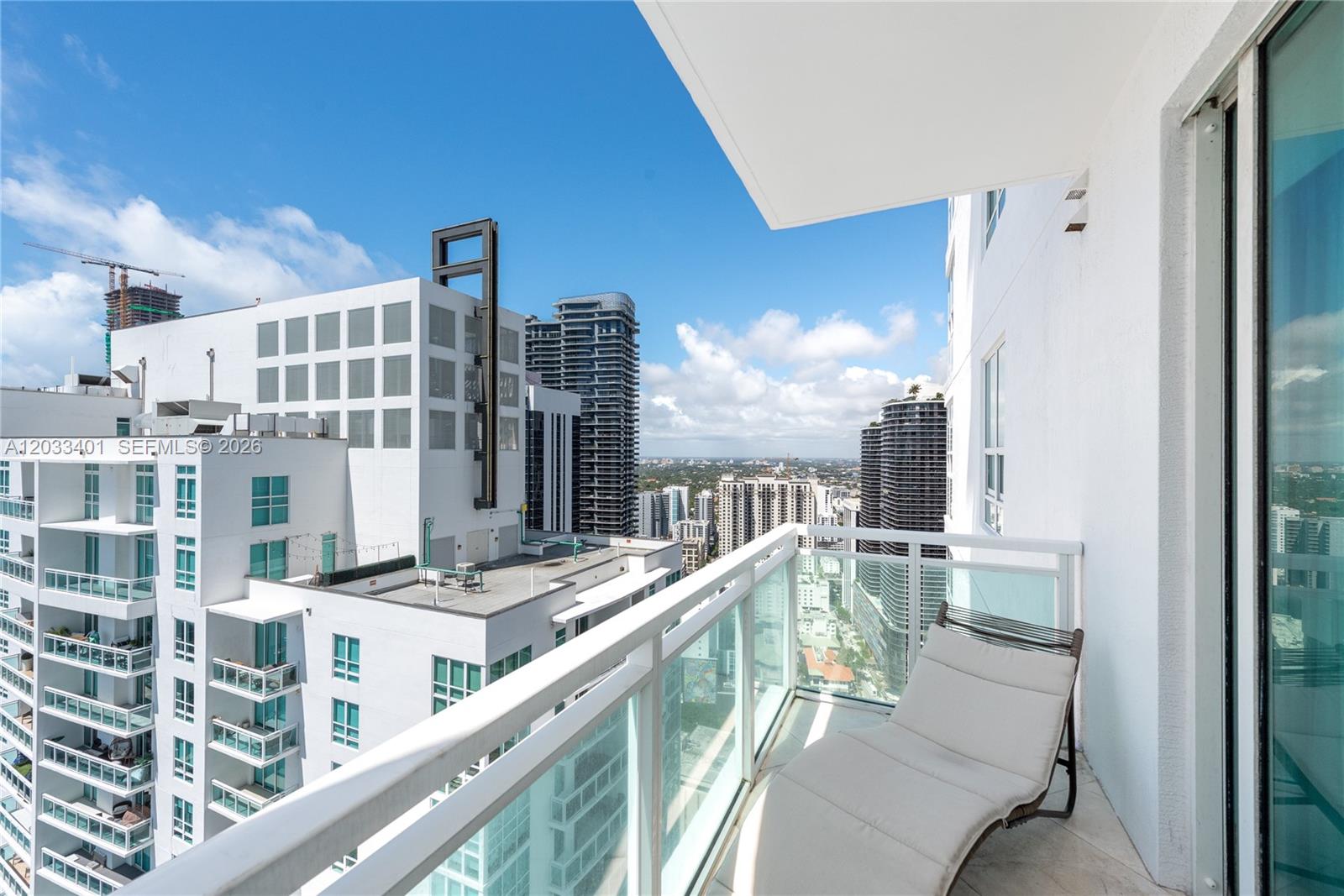 A high-rise balcony features a lounge chair overlooking a dense urban skyline — 950 Brickell Bay Dr # 4403, Miami FL 33131, MIAMI, FL