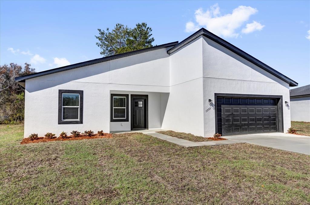 A white single-story house with a black roof, black trim, and a two-car garage — 13592 SW 40 CIRCLE, OCALA, FL