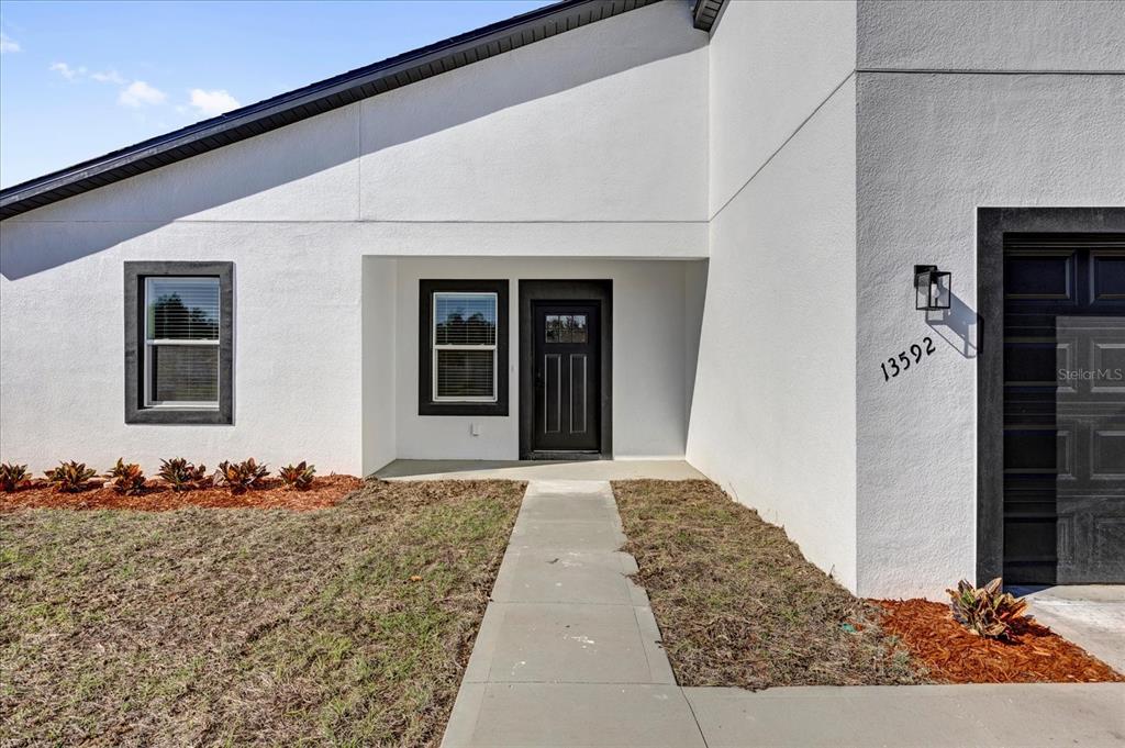 A white house exterior features a black front door, black window frames, and a walkway — 13592 SW 40 CIRCLE, OCALA, FL