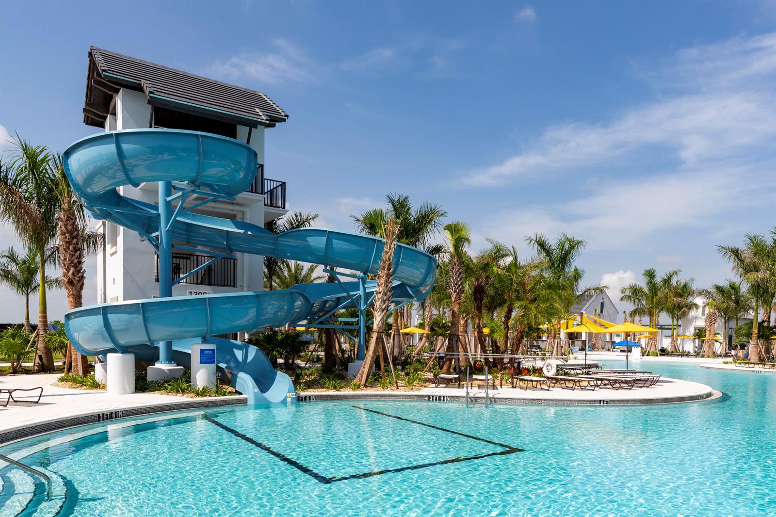 A blue spiral water slide descends into a swimming pool beside a multi-story building — 14141 Spruce Pine Drive, Westlake FL 33470, WESTLAKE, FL