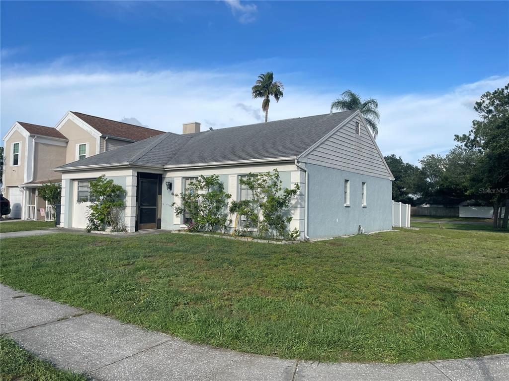 A light blue, single-story house with a gray shingled roof and a front lawn — 11001 SUNSWEPT PLACE, TAMPA, FL