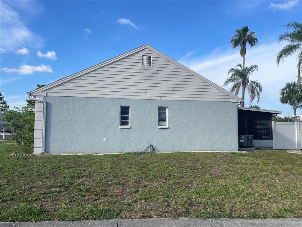 The exterior side view of a house features light blue stucco walls and horizontal siding — 11001 SUNSWEPT PLACE, TAMPA, FL
