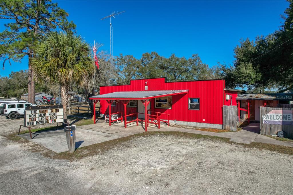 A red metal building with a covered porch and a sign advertising weekly events — 2451 SE HIGHWAY 41, MORRISTON, FL