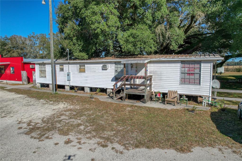 A white single-wide mobile home with a wooden porch sits on a gravel lot — 2451 SE HIGHWAY 41, MORRISTON, FL