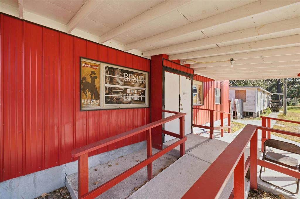 A red metal building exterior features a concrete ramp with railings and beer signage — 2451 SE HIGHWAY 41, MORRISTON, FL