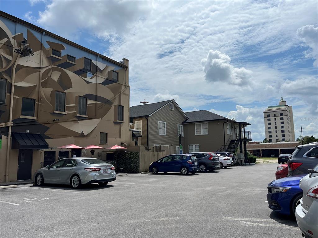 A parking lot sits in front of a mural-covered building and adjacent residential structures — 204 W UNIVERSITY AVENUE UNIT 8, GAINESVILLE, FL