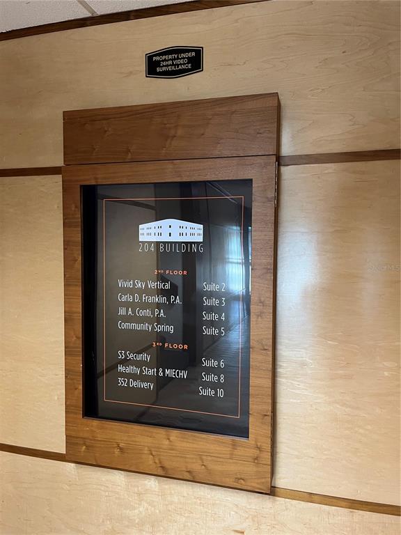 A directory sign for the 204 Building is mounted on a light wood-paneled wall — 204 W UNIVERSITY AVENUE UNIT 8, GAINESVILLE, FL