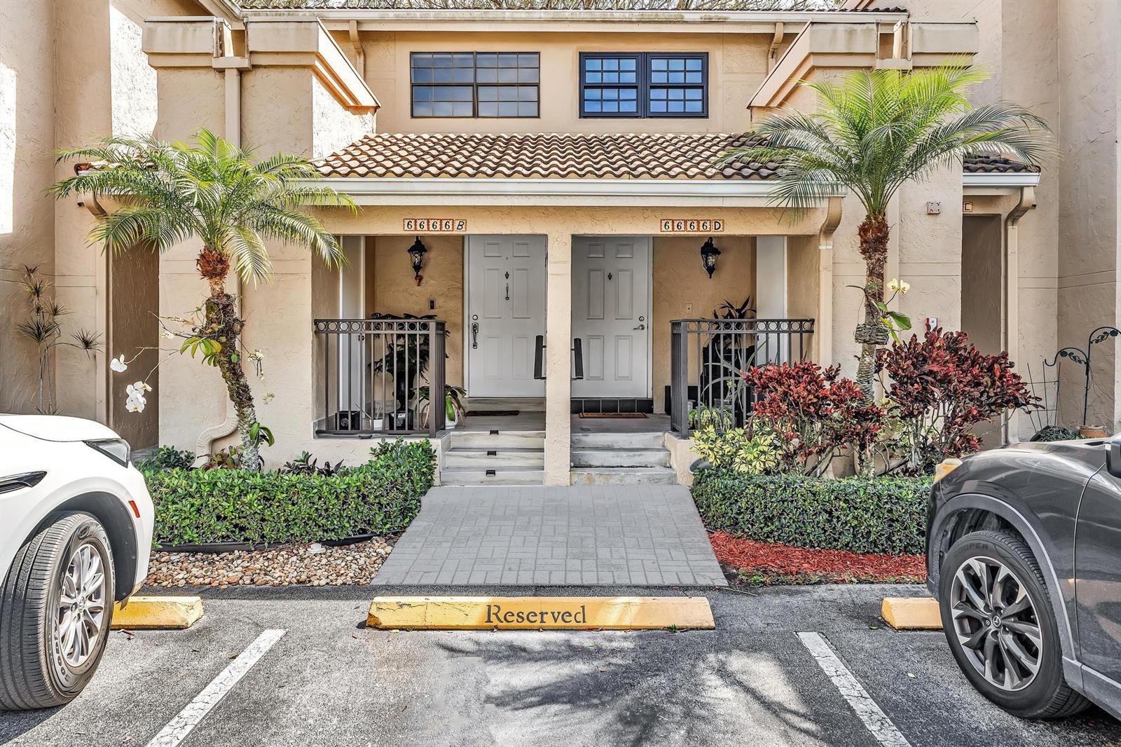 The exterior of a two-story townhouse complex features two white front doors and palm trees — 6666 Montego Bay Boulevard # B, Boca Raton FL 33433, BOCA RATON, FL