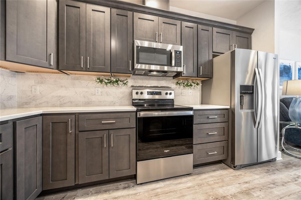 A kitchen features dark gray cabinets, stainless steel appliances, and white marble-style backsplash tiles — 12945 NW 12 ROAD, NEWBERRY, FL