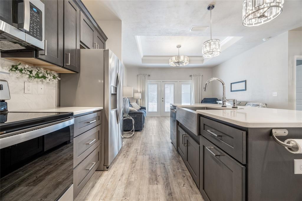A modern kitchen features dark gray cabinetry, stainless steel appliances, and a large farmhouse sink — 12945 NW 12 ROAD, NEWBERRY, FL