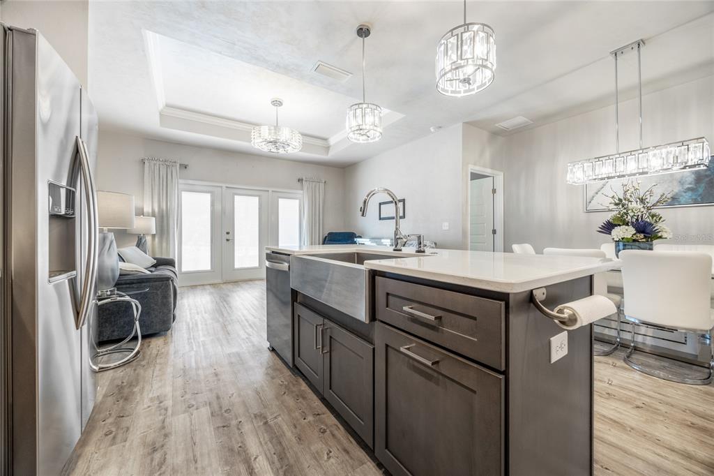A kitchen island with a farmhouse sink sits in front of a living and dining area — 12945 NW 12 ROAD, NEWBERRY, FL