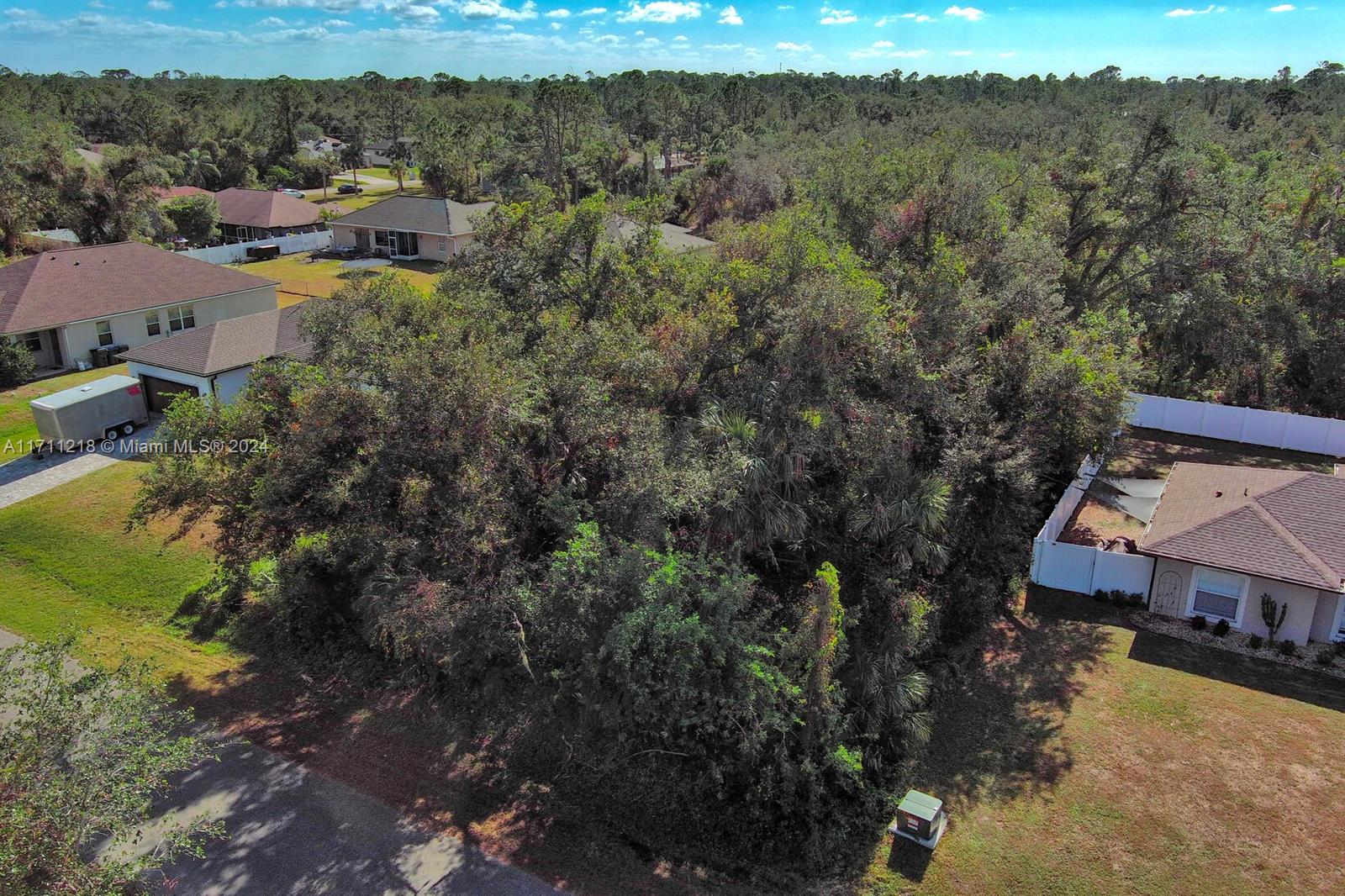 An aerial view shows a wooded vacant lot situated between two residential houses — #3 Sargon Ave, North Port FL 34287, NORTH PORT, FL