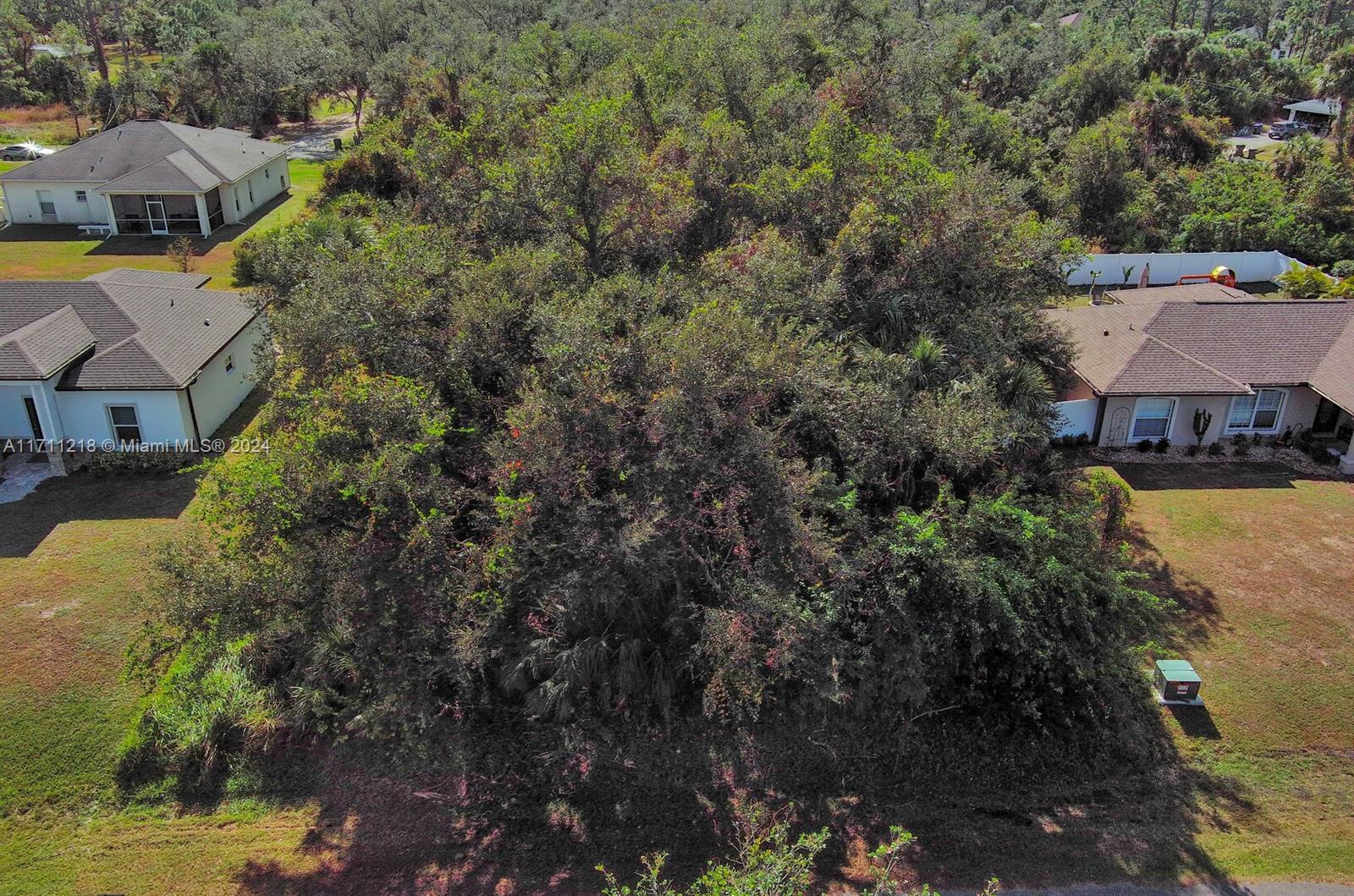 An aerial view shows a heavily wooded vacant lot situated between two residential houses — #3 Sargon Ave, North Port FL 34287, NORTH PORT, FL