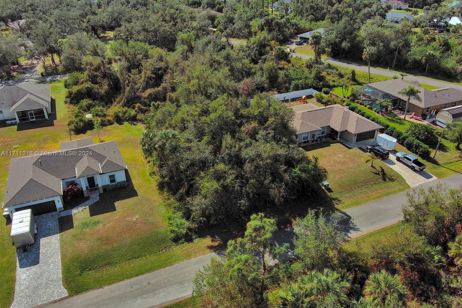 An aerial view shows a vacant, wooded lot situated between two single-family suburban homes — #3 Sargon Ave, North Port FL 34287, NORTH PORT, FL