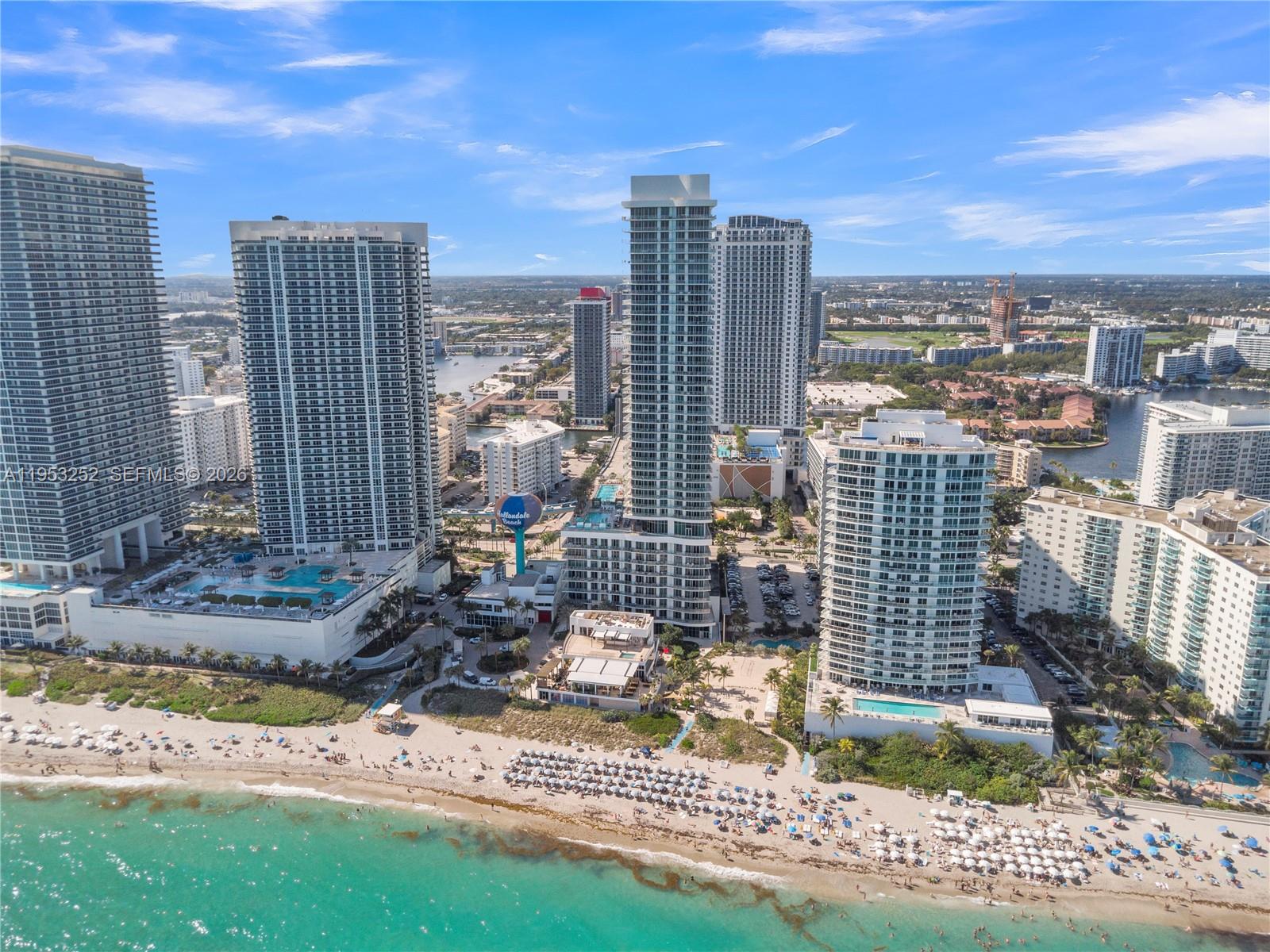 An aerial view shows several high-rise residential towers situated along a sandy beach — 4111 S Ocean Dr # 1507, Hollywood FL 33019, HOLLYWOOD, FL