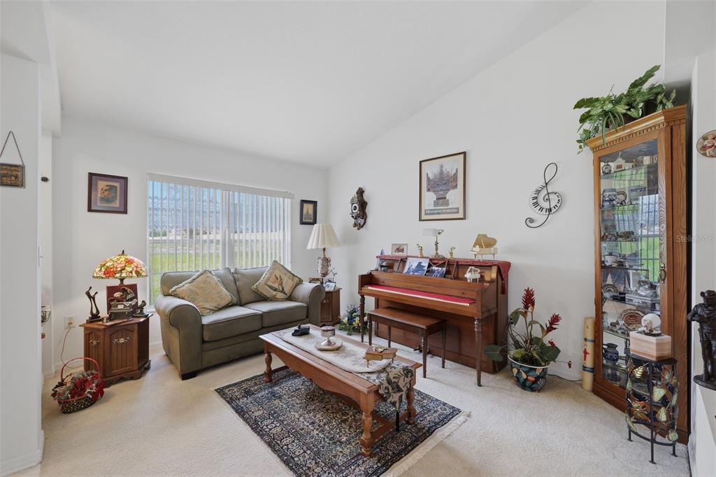 A living room features a sofa, a piano, a coffee table, and a display cabinet — 2384 LEMA DRIVE, SPRING HILL, FL