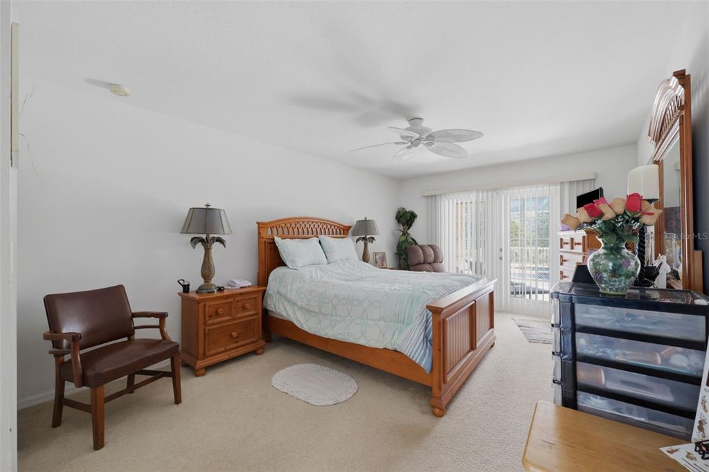 A bedroom features a wooden bed frame, a leather chair, and a sliding glass door — 2384 LEMA DRIVE, SPRING HILL, FL