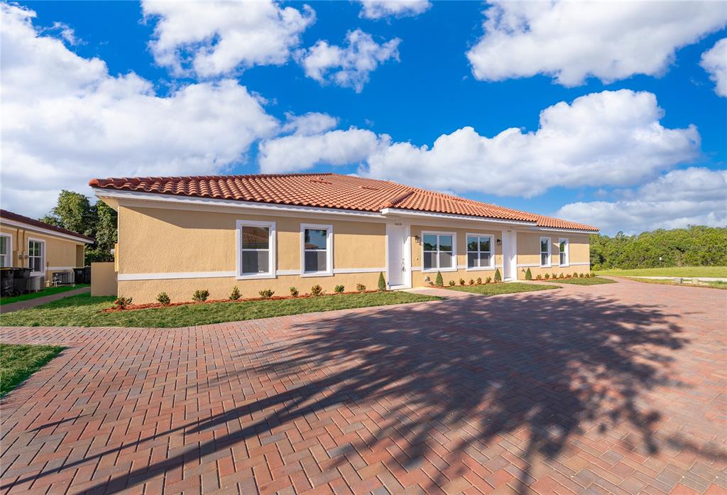 A single-story duplex with a terracotta tile roof and a brick paver driveway — 1657 CUMIN DRIVE, KISSIMMEE, FL
