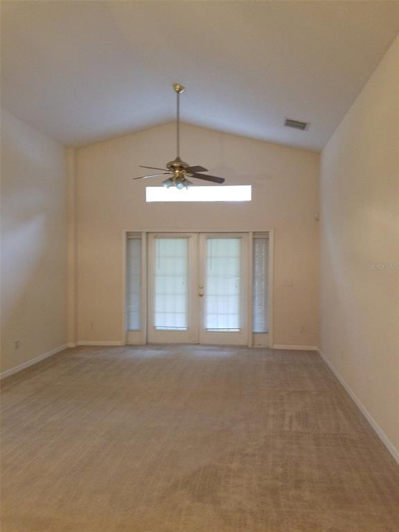 A living room with beige carpet, vaulted ceilings, a ceiling fan, and glass double doors — 19551 GLEN ELM WAY, ORLANDO, FL