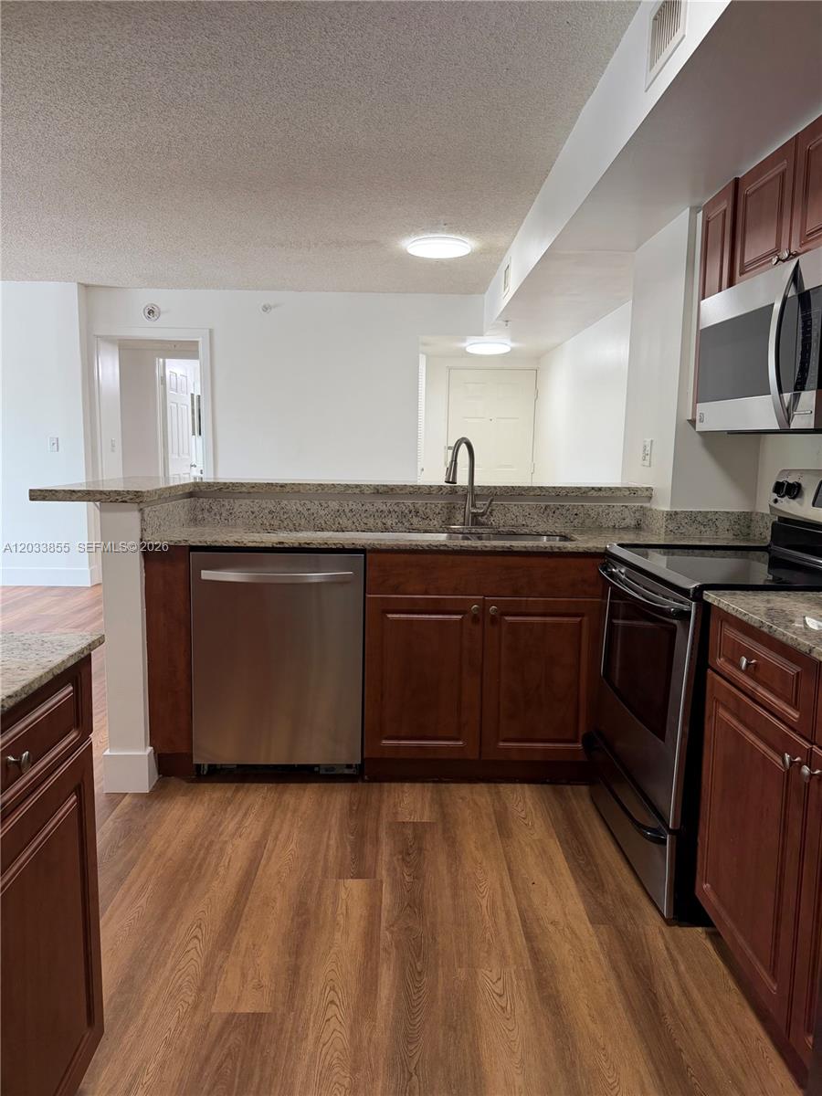 A kitchen features dark wood cabinets, stainless steel appliances, and granite countertops — 2620 S University Dr # 209, Davie FL 33328, DAVIE, FL