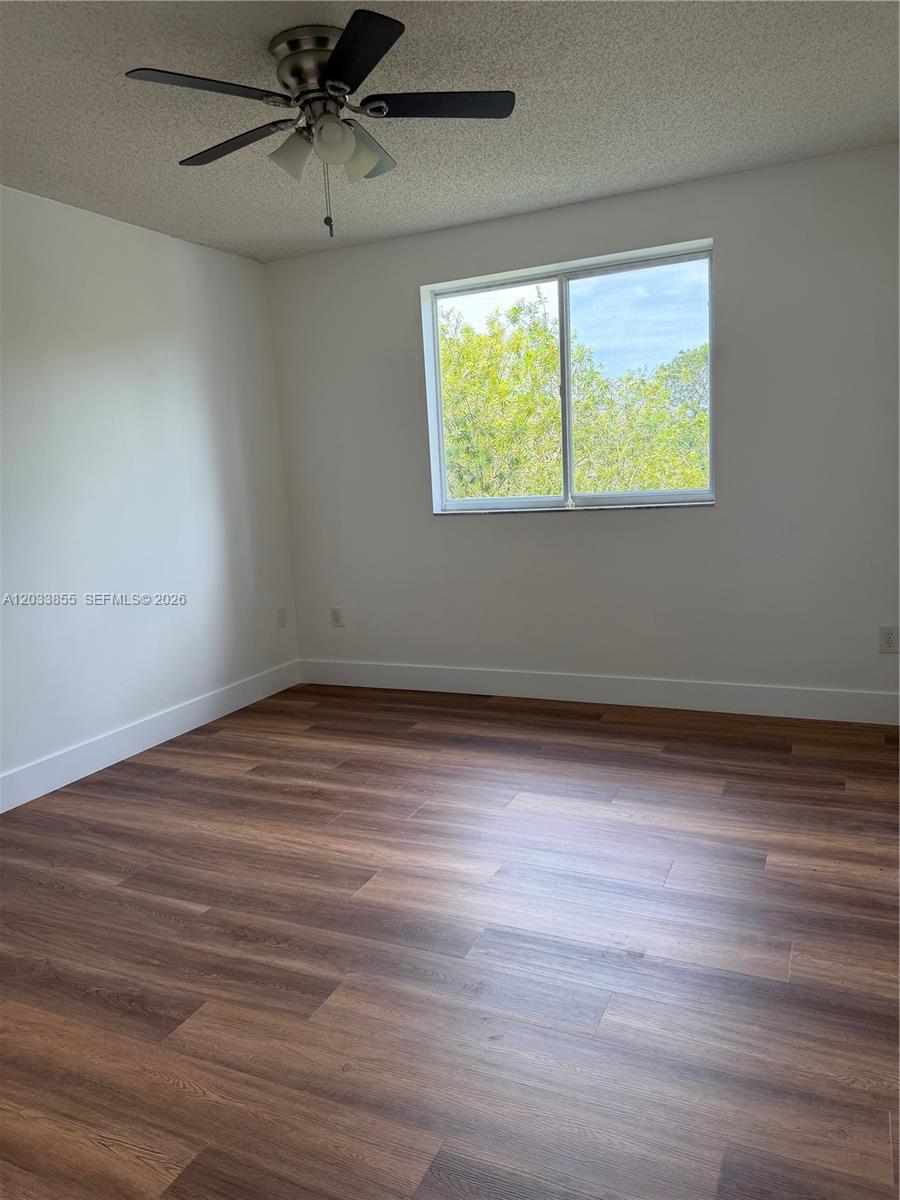 A bedroom with white walls, wood-look flooring, a ceiling fan, and a single window — 2620 S University Dr # 209, Davie FL 33328, DAVIE, FL