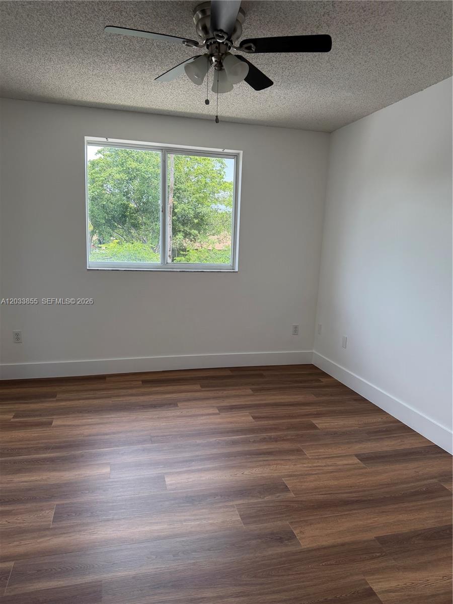 An empty bedroom features white walls, wood-look flooring, a ceiling fan, and a window — 2620 S University Dr # 209, Davie FL 33328, DAVIE, FL