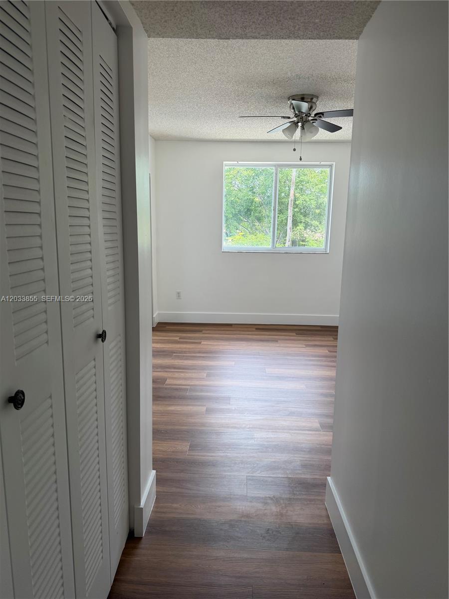 A view through a doorway into a bedroom with wood-look flooring and a ceiling fan — 2620 S University Dr # 209, Davie FL 33328, DAVIE, FL