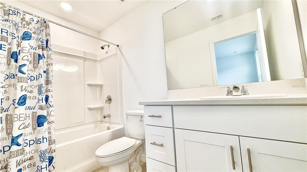 A bathroom features a white vanity, a large mirror, a toilet, and a tub-shower combo — 3244 SKYLINE LOOP, KISSIMMEE, FL