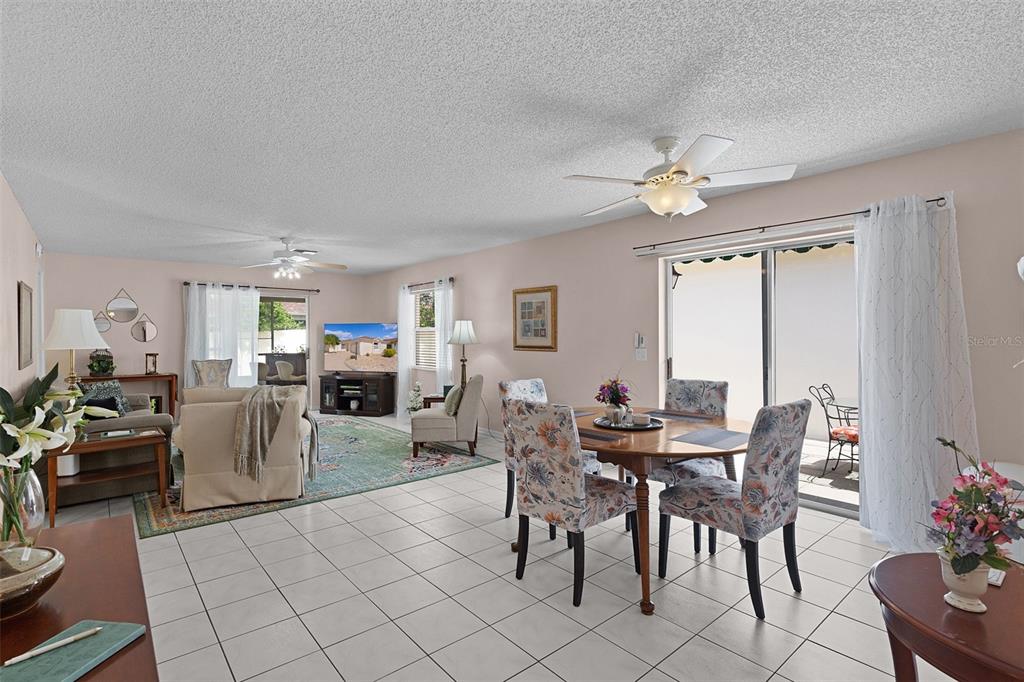 An open-concept living and dining area features tile flooring, a ceiling fan, and sliding doors — 1330 LA JOLLA CIRCLE, THE VILLAGES, FL