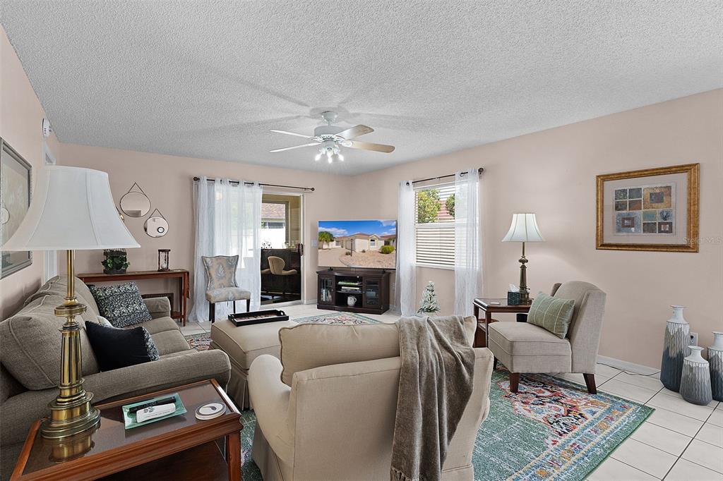 A living room features a sofa, armchairs, a television, and a ceiling fan — 1330 LA JOLLA CIRCLE, THE VILLAGES, FL