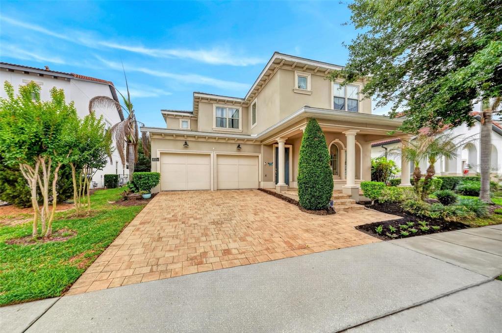 A two-story suburban house with a beige stucco exterior, a paved driveway, and a garage — 15554 PANTHER LAKE DRIVE, WINTER GARDEN, FL