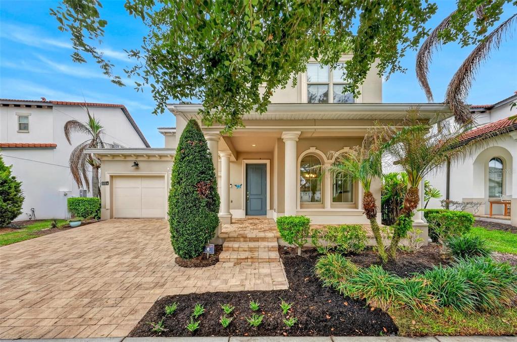 A two-story house with a beige exterior, a paved driveway, and a covered front porch — 15554 PANTHER LAKE DRIVE, WINTER GARDEN, FL