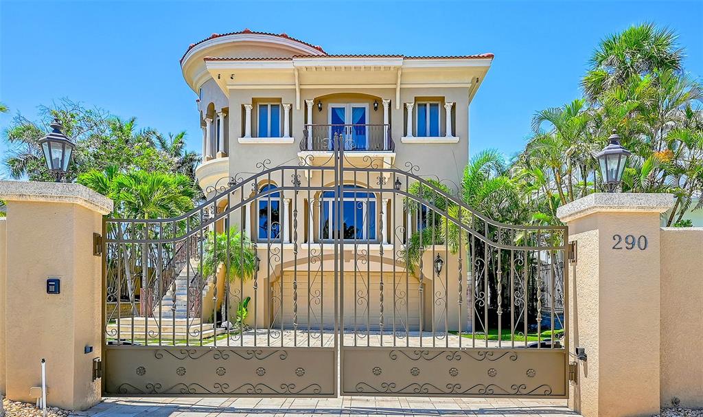 A three-story Mediterranean-style house is viewed through a large, ornate metal gate — 290 N WASHINGTON DRIVE, SARASOTA, FL