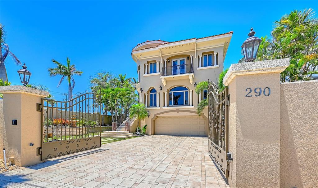 A three-story house with a beige stucco exterior, arched windows, and a gated paved driveway — 290 N WASHINGTON DRIVE, SARASOTA, FL