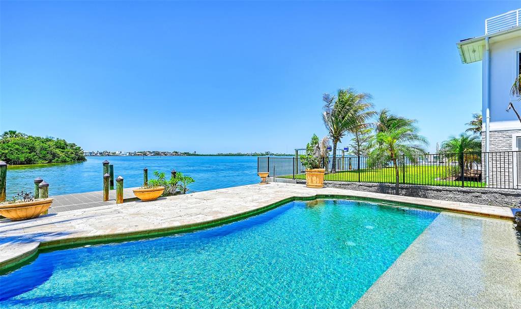 A swimming pool sits on a stone patio overlooking a bay with a dock — 290 N WASHINGTON DRIVE, SARASOTA, FL